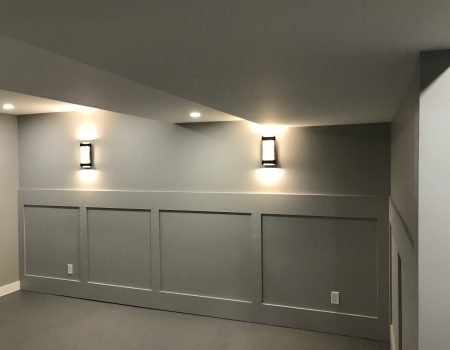 Finished basement with decorative wall paneling and modern lighting in Stoney Creek renovation