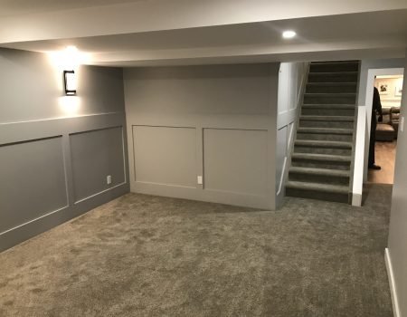 Modern finished basement living space with carpet flooring and stair access in Stoney Creek home renovation